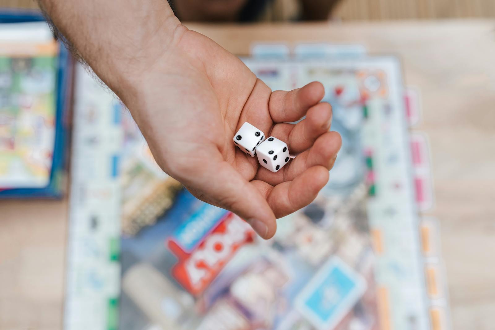 Close-up of a hand holding dice over a colorful board game, highlighting playful moments.